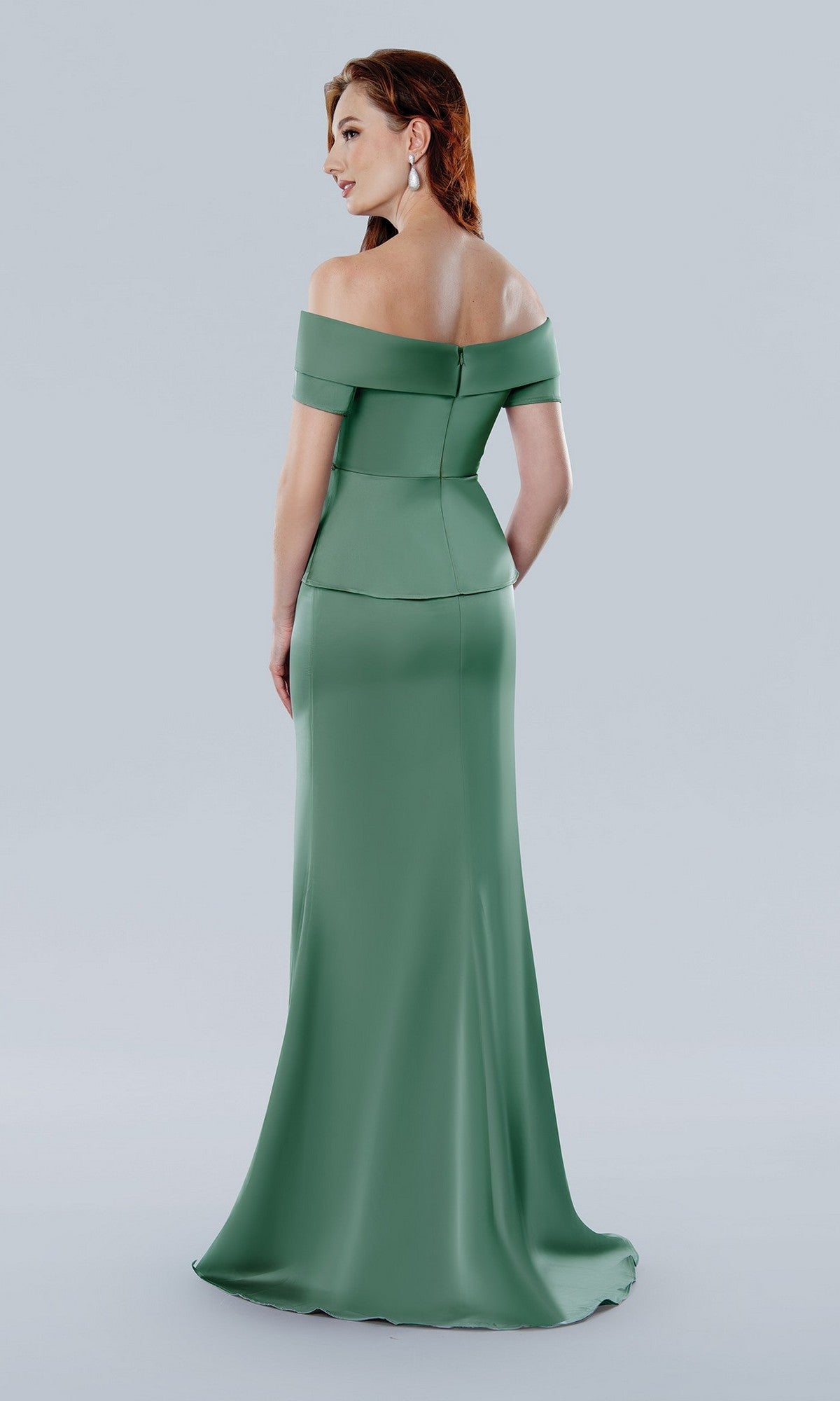 A woman wearing the Stella Couture 25309 long formal sage dress with an off-the-shoulder sweetheart neckline and beaded waist stands against a plain light gray background, facing away from the camera.